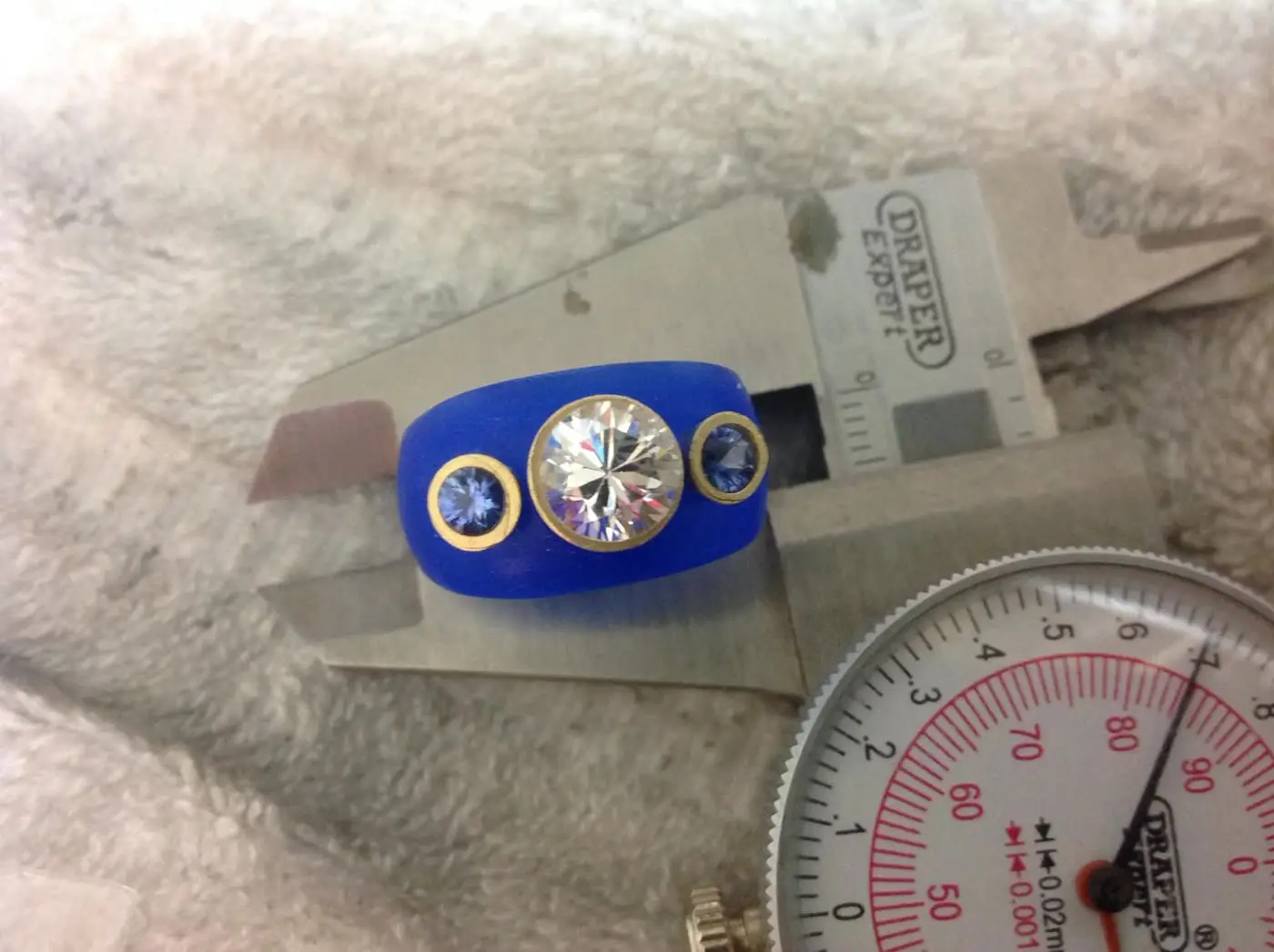 A diamond and sapphire ring modelled in blue setter's wax, measured with gauges